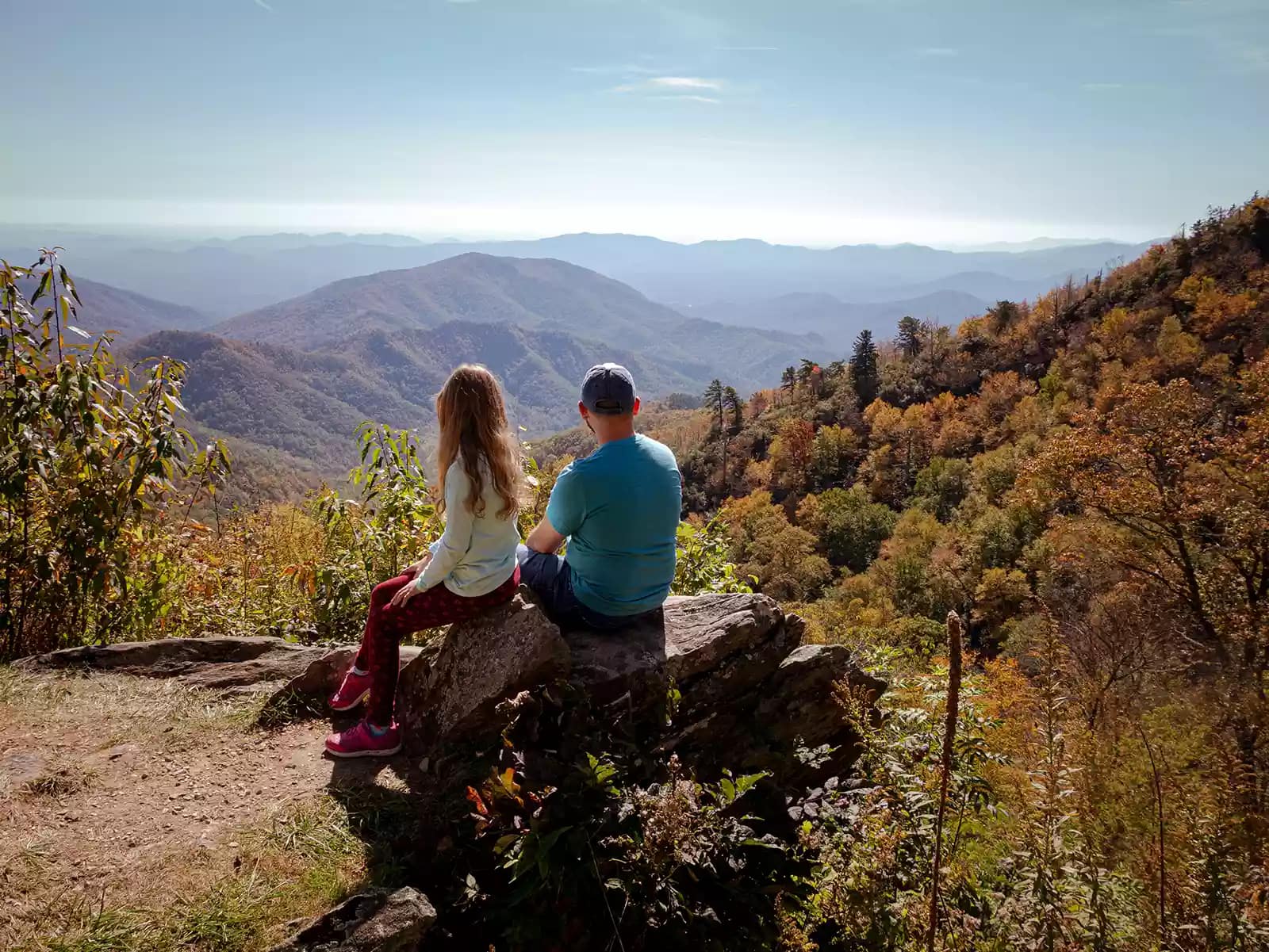 girl and man sitting overlooking mountain range