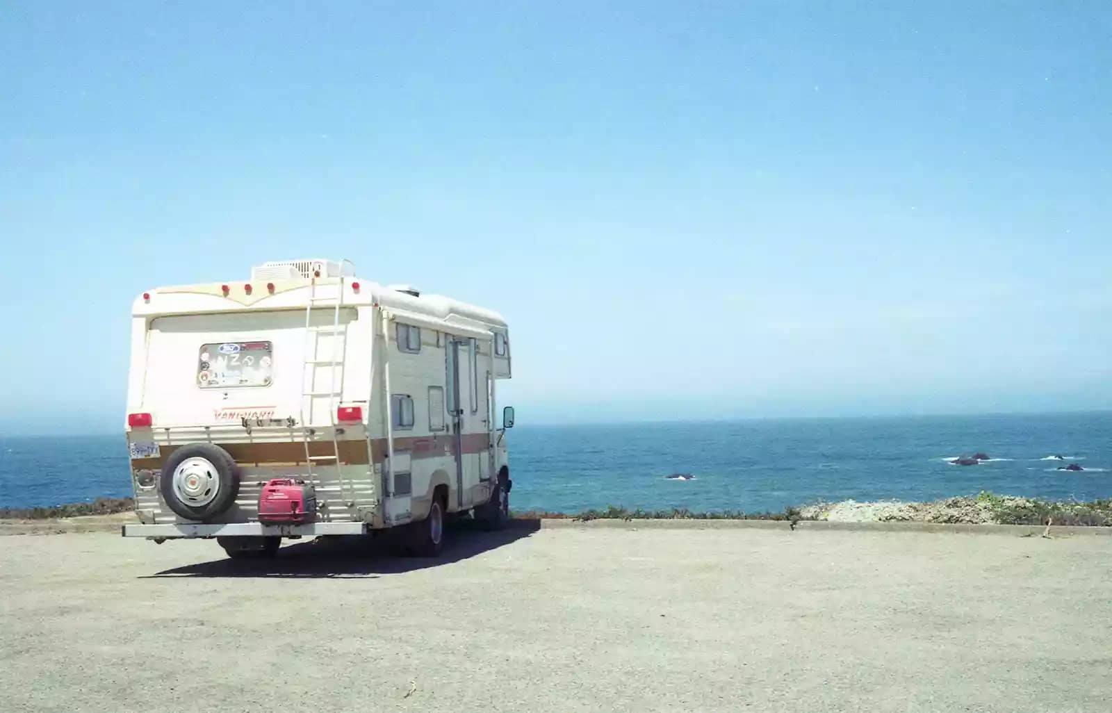 gold and white camper parked facing the ocean