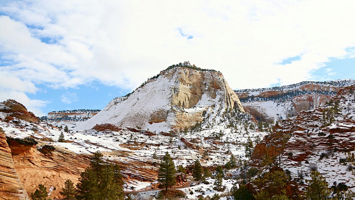 Section of Zion National park showing sparse trees and a rock formation lightly mblanketed in snow in the winter, photo by Daniel Bae.