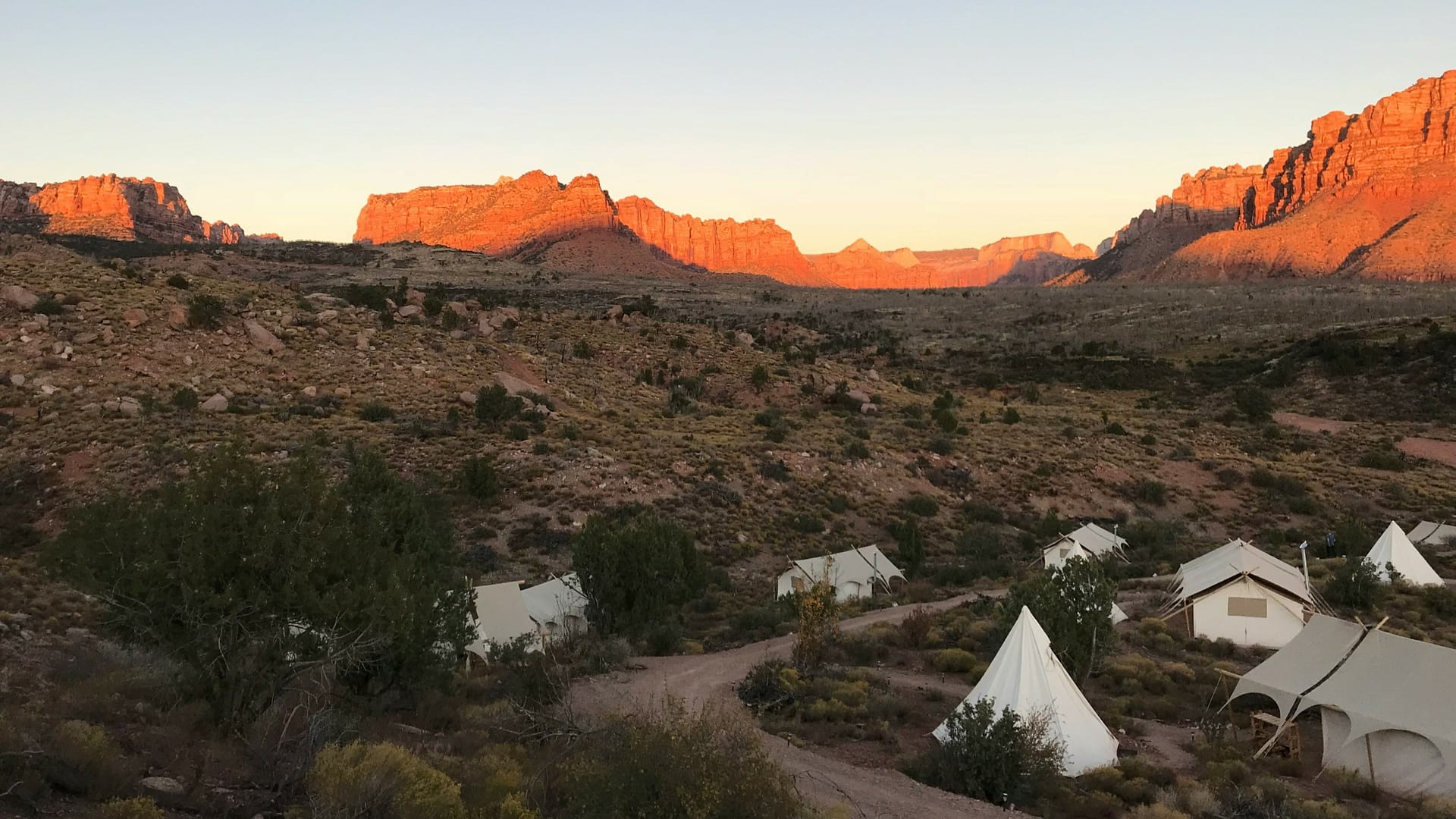 A glamping area overlooking the rock formations and mountains of Zion National Park around sunset. Photo by Bulent Keles.