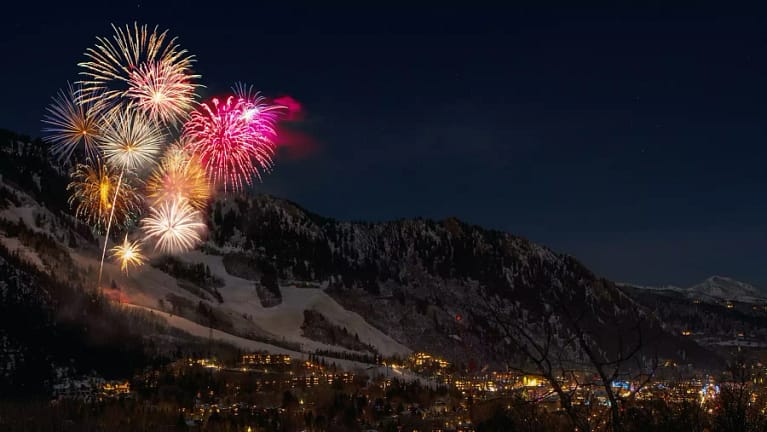 fireworks over mountains with town in the valley below