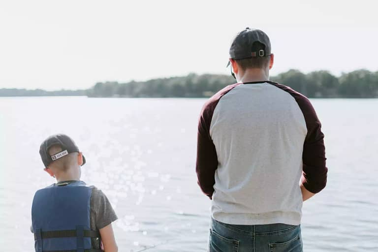 man and boy fishing lakeside facing away from camera