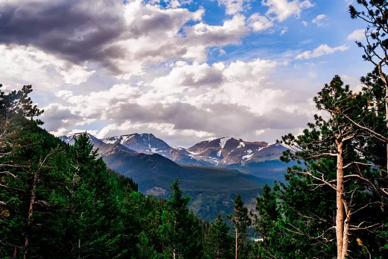 Snow-capped peaks are framed by pine trees in Rocky Mountain National Park, one of the best places to visit when you travel to Colorado.