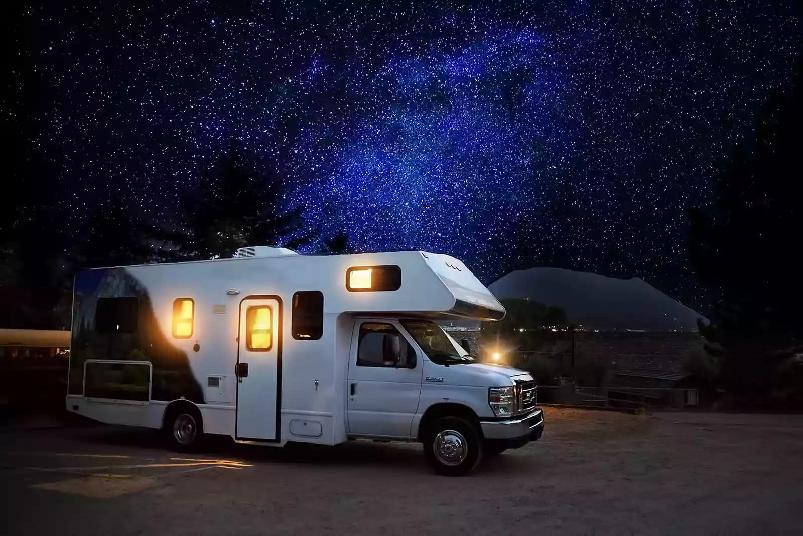 white RV parked at night with light on inside]