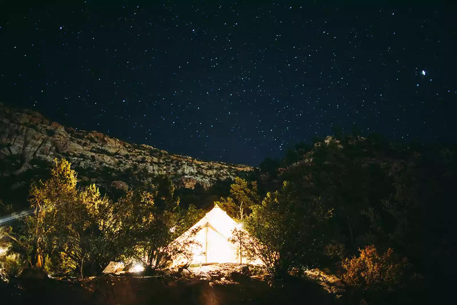 white yurt light up against mountainous night sky