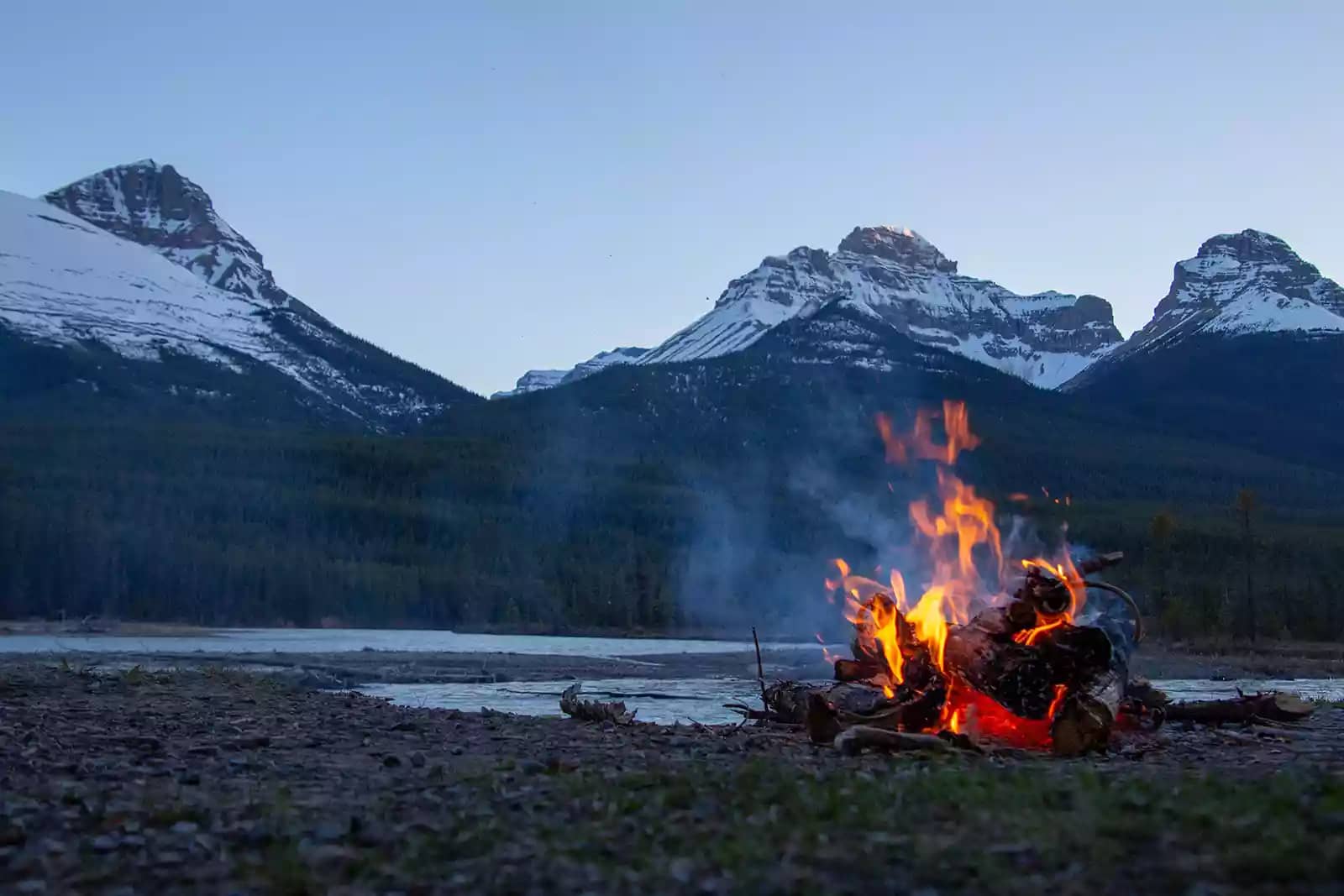 campfire beside a snow-capped mountain range in Colorado