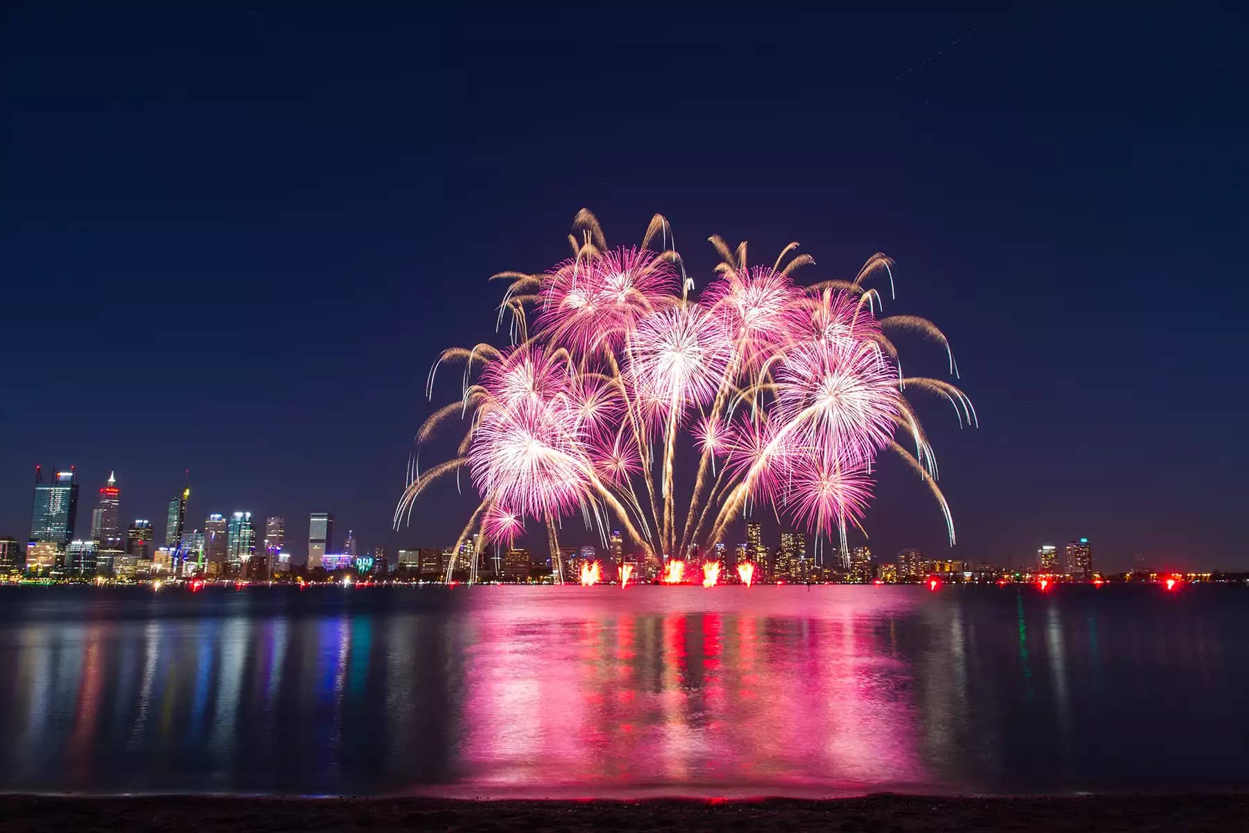 fireworks display over a lake with city skyline