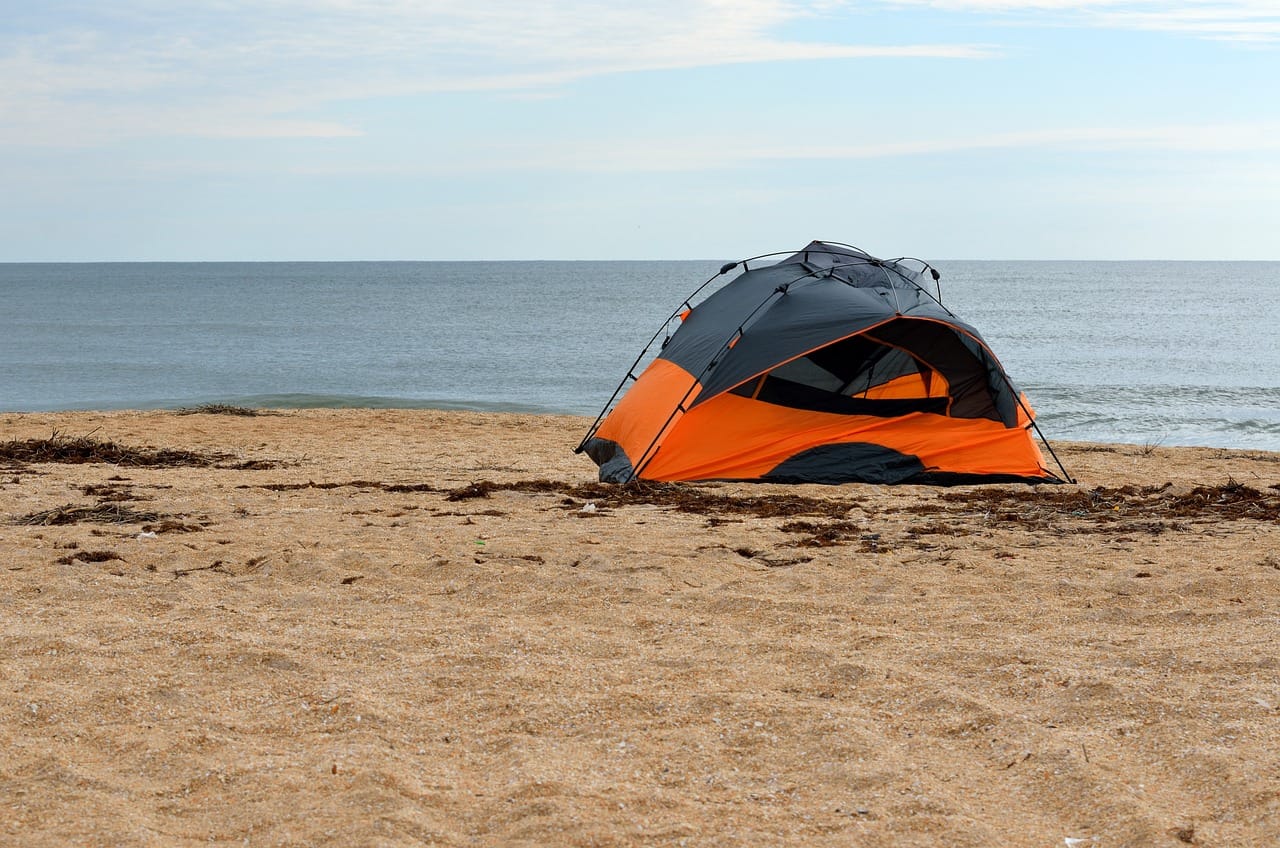 orange and gray tent set up on sandy beach to convey camping near St. Augustine